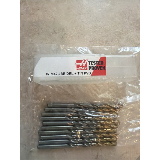 Packaged set of ten gold-coated metal drill bits with white label reading "Haas Tested Proven #7 M42 JBR DRL + TIN PVD" against concrete background.