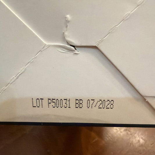 Close-up of white ceiling or box top with printed lot number "LOT P3M21 EB 072228" and visible seams and mounting hardware.