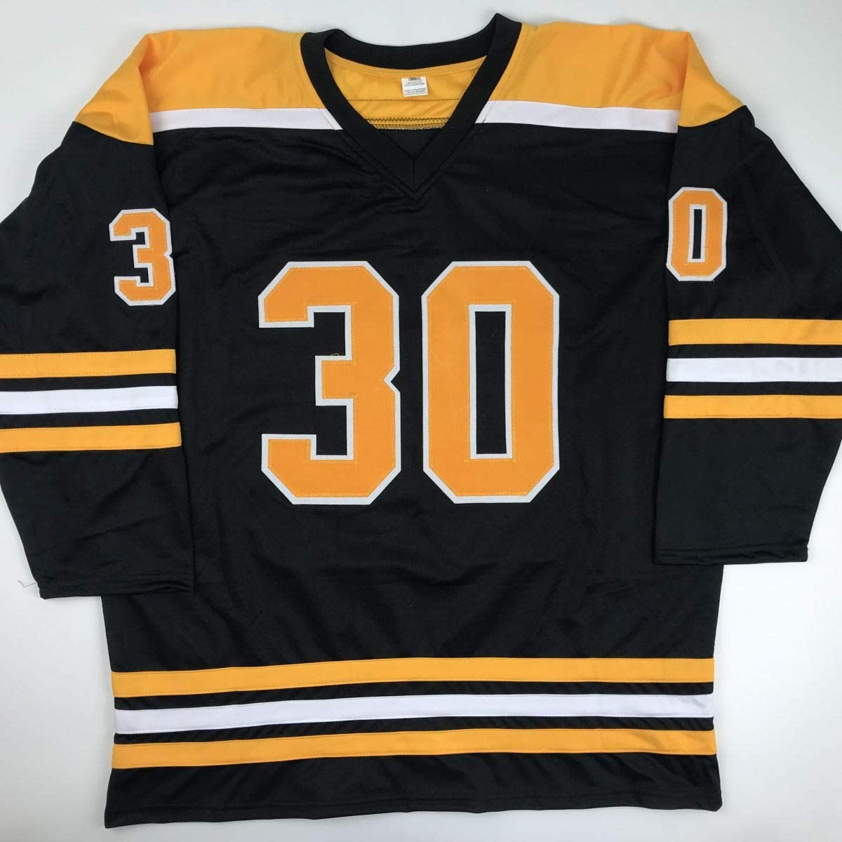 Black and gold hockey jersey with number 30 displayed front and center, laid flat against white background.