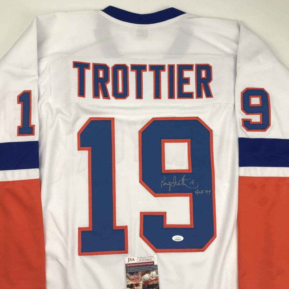 Rear view of white hockey jersey with navy and red striped sleeves, displaying "TROTTIER" and number 19, with visible autograph and JSA authentication label.