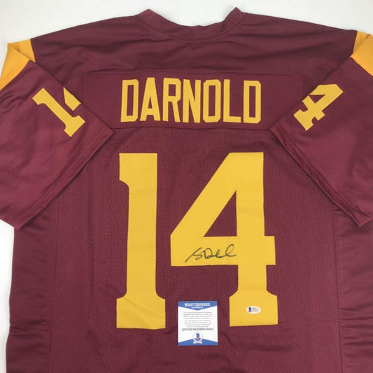 Back view of maroon and gold USC football jersey number 14 with "DARNOLD" nameplate and signature, displaying JSA authentication certificate.
