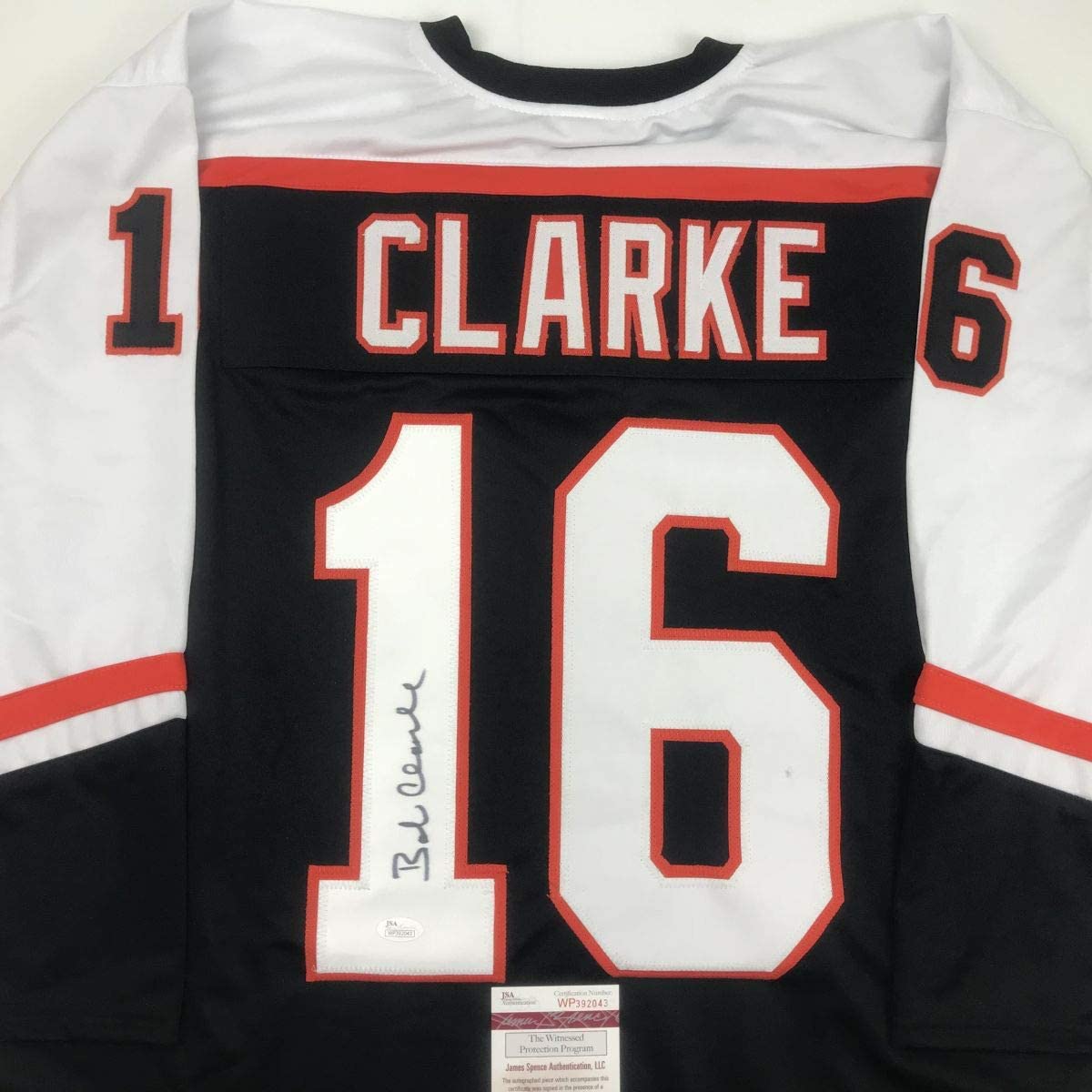 Back view of signed black Philadelphia Flyers hockey jersey number 16 with Clarke name and JSA authentication label visible.