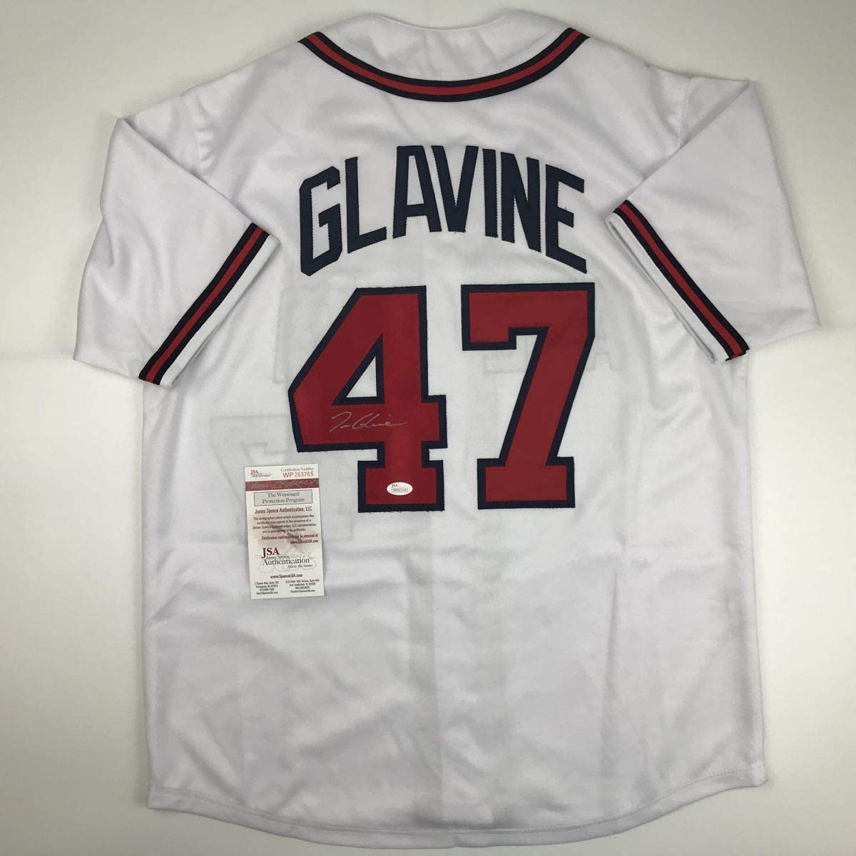 Back view of white baseball jersey displaying "GLAVINE" and number 47 in red and navy with JSA authentication label attached.