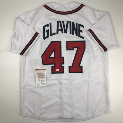 Back view of white baseball jersey displaying "GLAVINE" and number 47 in red and navy with JSA authentication label attached.