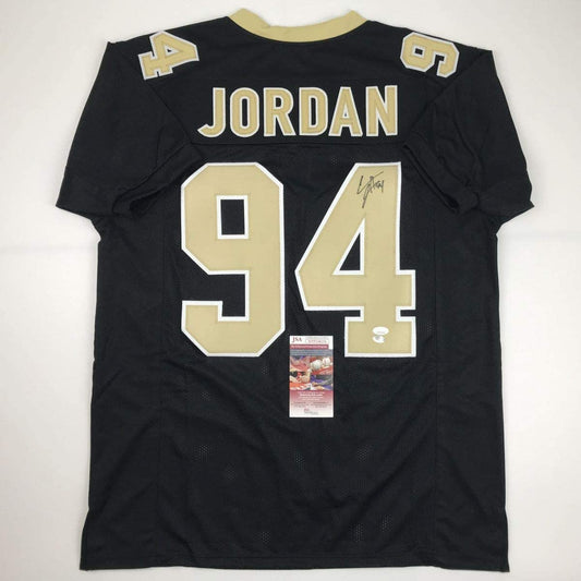 Back view of black New Orleans Saints football jersey number 94 with "JORDAN" name and JSA authentication certificate visible.
