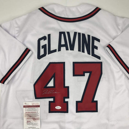 Back view of white baseball jersey with "GLAVINE" and red number 47, navy and red trim, signed, with JSA authentication certificate visible.