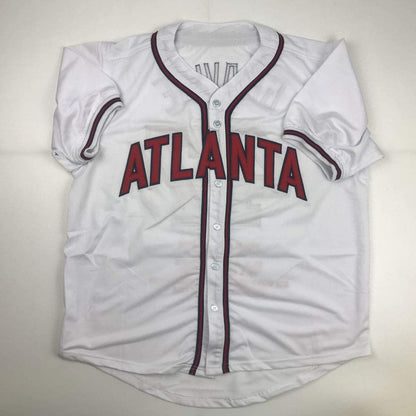 White Atlanta Braves baseball jersey with red lettering and maroon piping, displayed flat against neutral background.