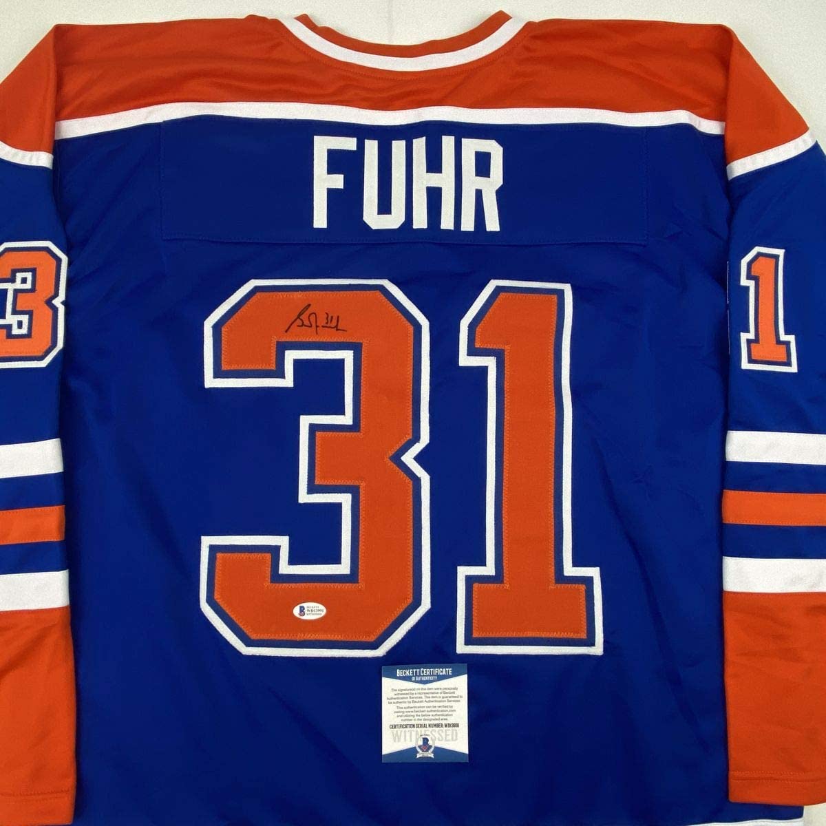 Back view of blue Edmonton Oilers hockey jersey number 31 with "FUHR" name and autographed signature, Beckett authentication sticker visible.
