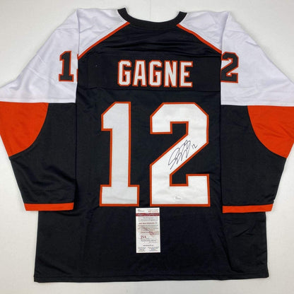 Back view of signed black and orange hockey jersey number 12 with "GAGNE" nameplate and JSA authentication certificate attached.