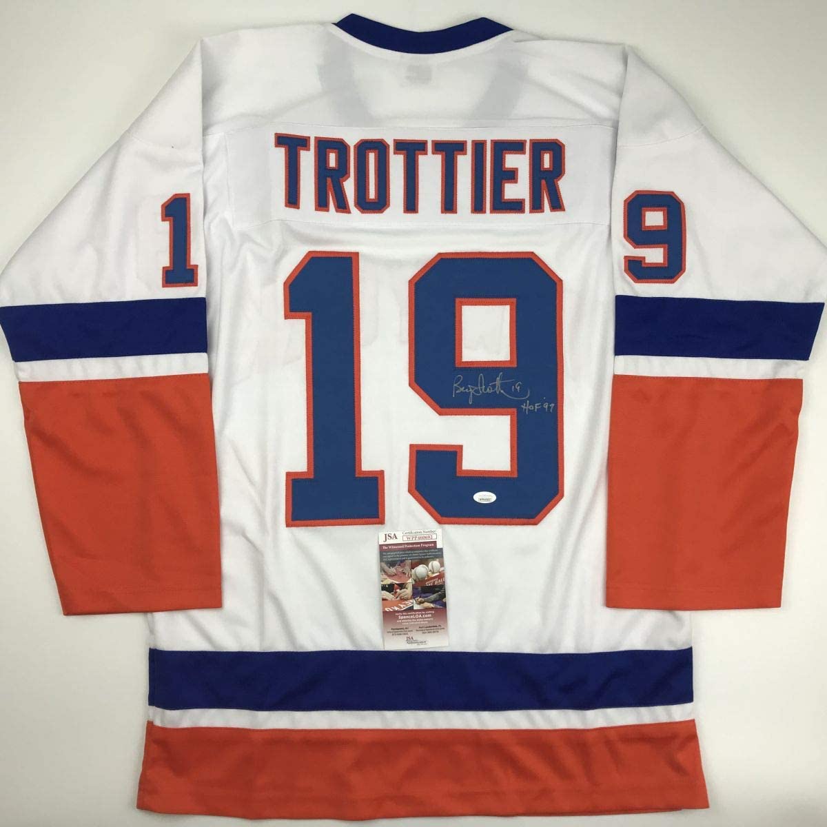 Rear view of white, navy, and red hockey jersey number 19 with "TROTTIER" nameplate and autographed inscription, displaying JSA authentication certificate.