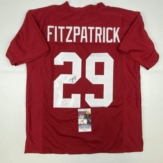 Red Alabama football jersey with white "FITZPATRICK 29" on back, displayed flat with JSA authentication certificate visible below neckline.