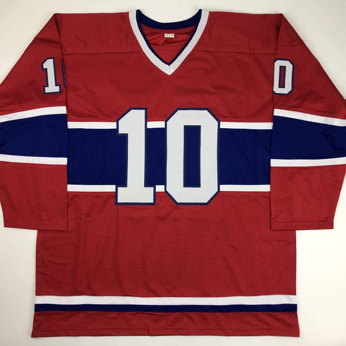 Red and navy Montreal Canadiens hockey jersey with large white number 10 displayed flat against white background.