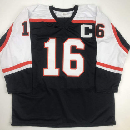 Black, red, and white hockey jersey displayed flat showing front with white number 16 and "C" captain patch.