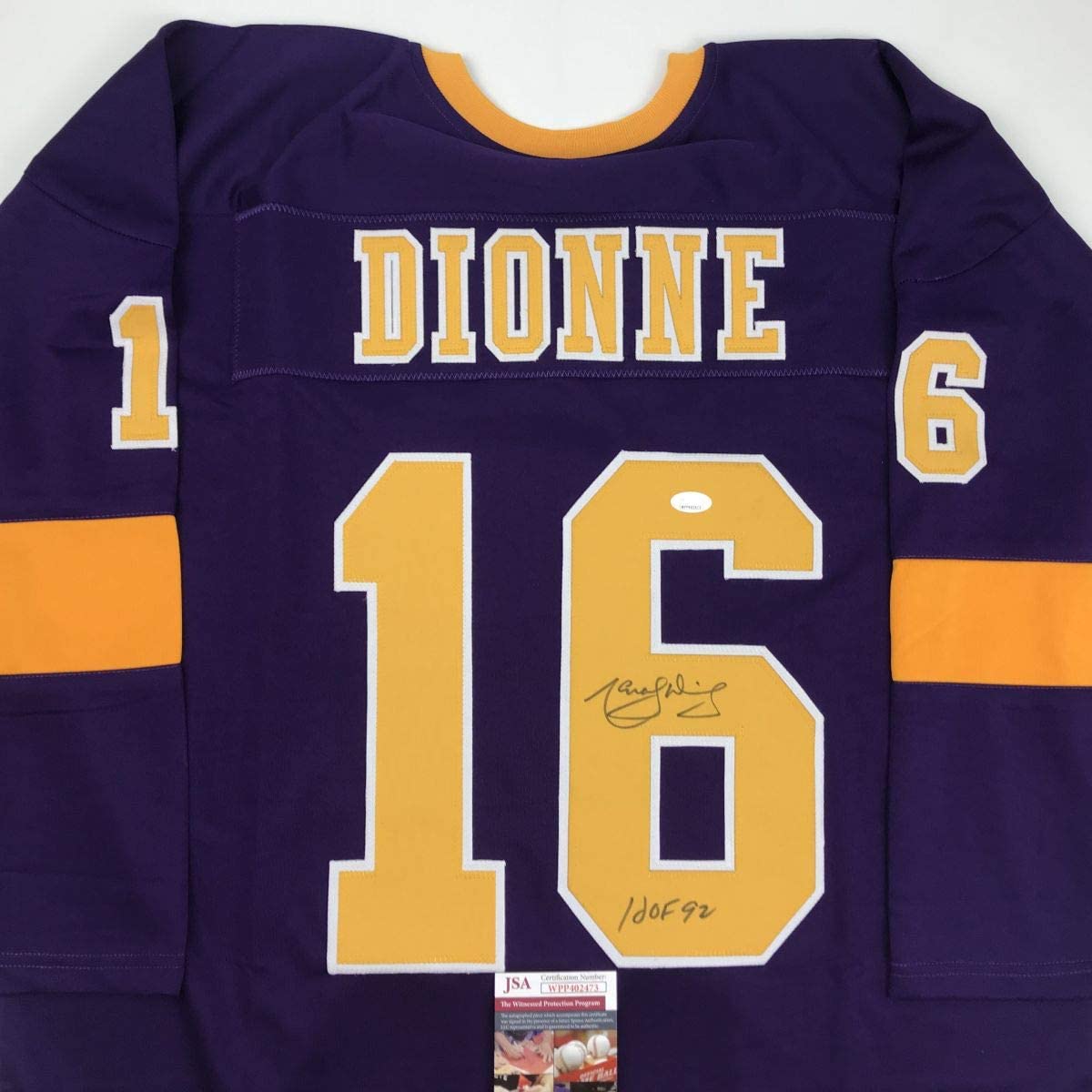 Purple Los Angeles Dionne hockey jersey number 16 with gold and white lettering, displayed flat showing front with signature and JSA authentication certificate.