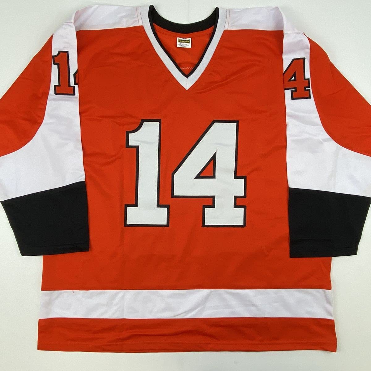 Front view of red, white, and black hockey jersey number 14 laid flat against white background.