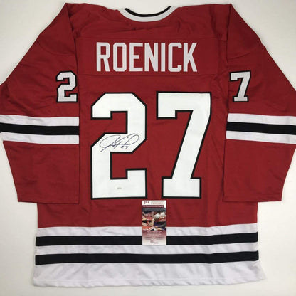 Flat lay of red Chicago Blackhawks hockey jersey number 27 signed by Jeremy Roenick with JSA authentication certificate attached.