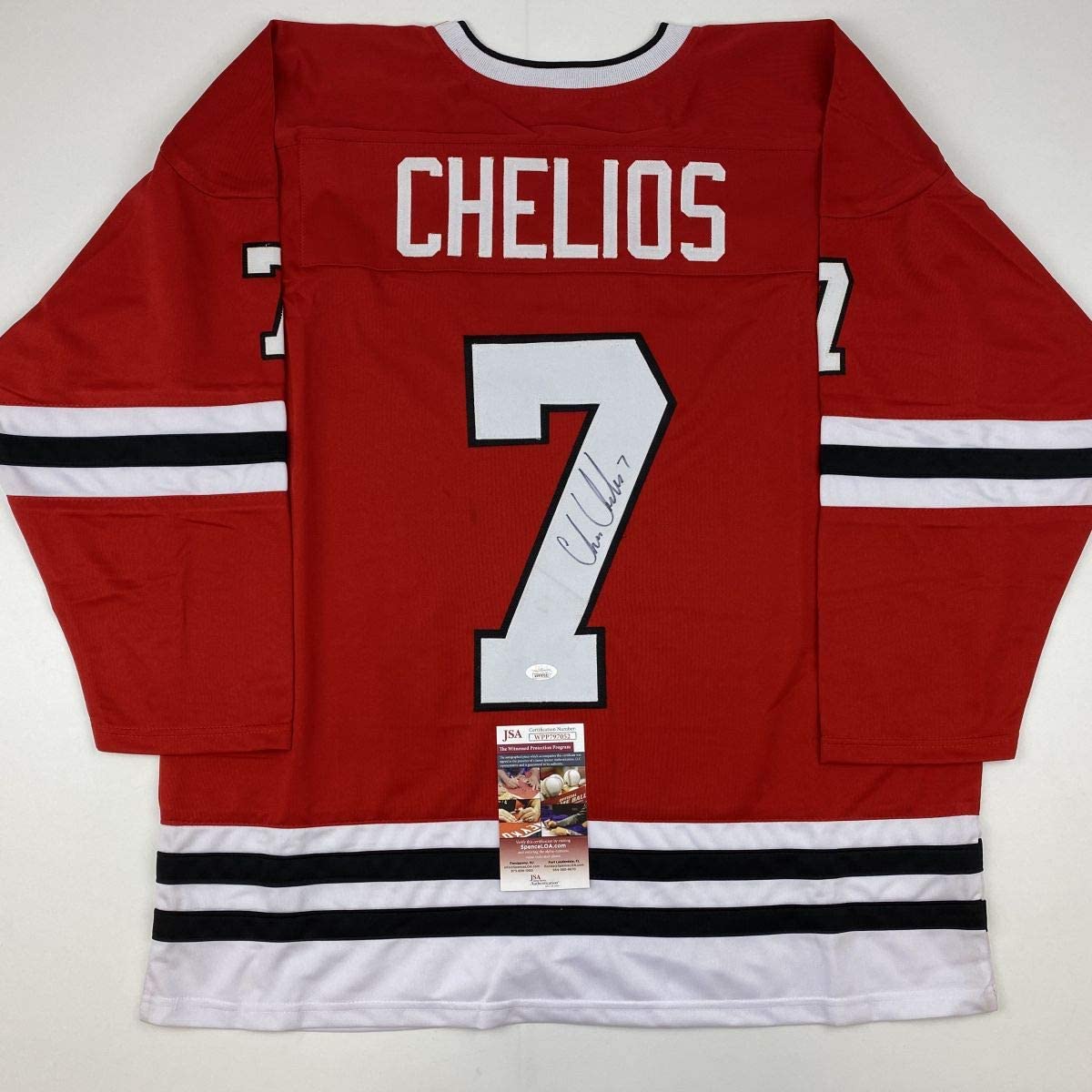 Red Chicago Blackhawks hockey jersey number 7 signed by Chris Chelios, displayed flat with JSA authentication certificate visible at bottom.