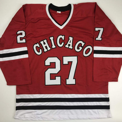 Red Chicago hockey jersey with white and black striped trim, displaying "CHICAGO" and number 27 across chest, laid flat on white background.