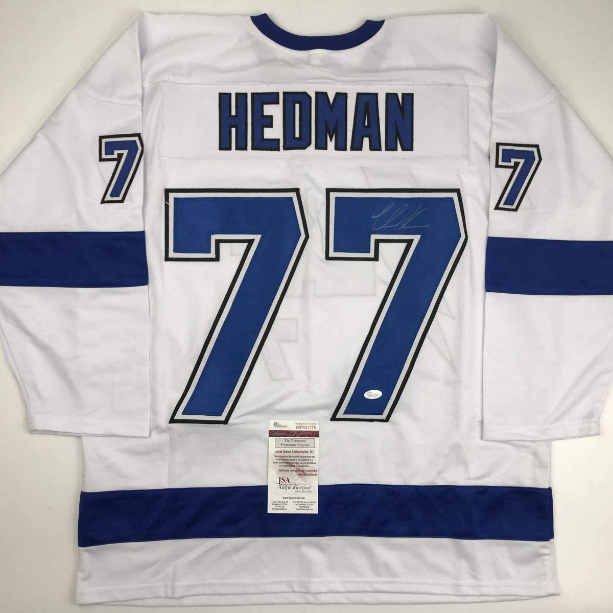 White hockey jersey with blue sleeves and stripes displaying "HEDMAN" and number 77, with JSA authentication certificate visible at center bottom.