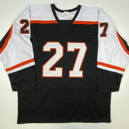 Black hockey jersey with white and red sleeves displaying number 27 in white with red outline, flat lay view.