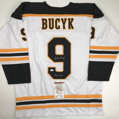 White hockey jersey with black and orange stripes displaying "BUCYK" and number 9, signed and authenticated with JSA certificate visible.