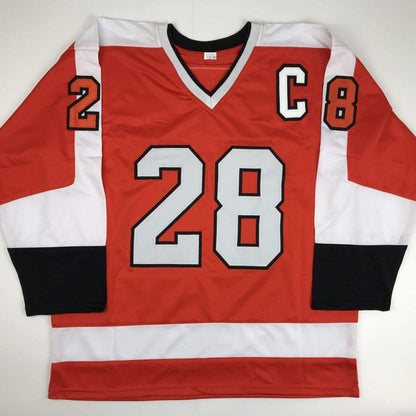 Red, white, and black hockey jersey displayed flat showing front with number 28 and captain C patch.