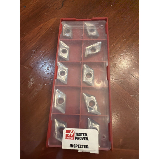 Red plastic storage case containing ten metallic diamond-shaped carbide inserts with center holes, labeled "TESTED. PROVEN. INSPECTED.
