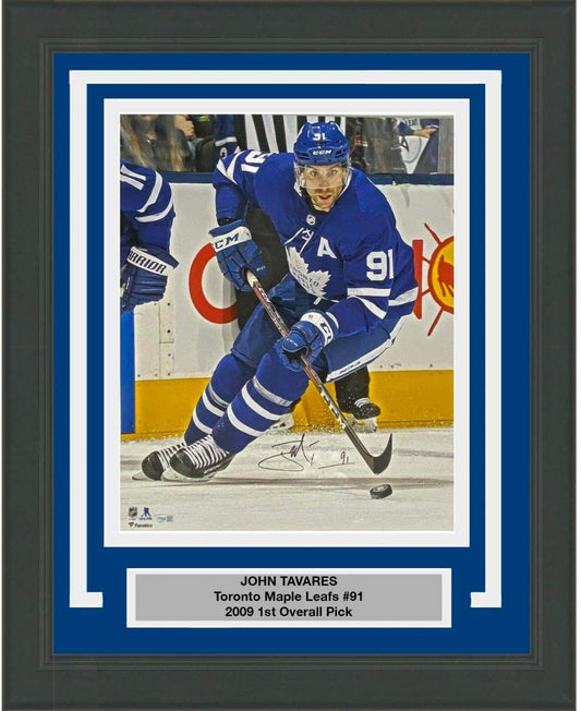 Signed photo of John Tavares in Toronto Maple Leafs blue jersey number 91 skating with hockey stick, mounted in blue and white matting with nameplate.