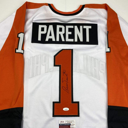 Signed white hockey jersey with orange and black trim displaying "PARENT" nameplate and number 1, with JSA authentication certificate visible at bottom.