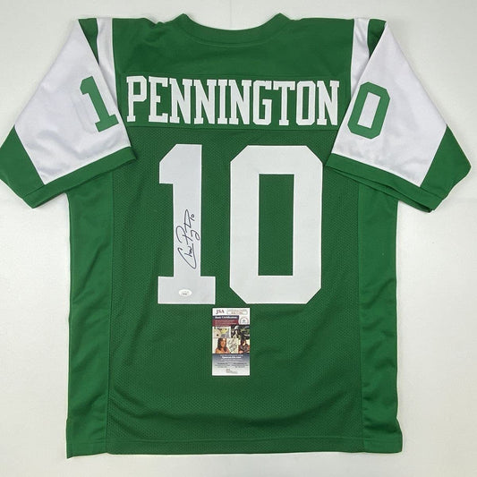 Flat lay of green and white football jersey #10 with "PENNINGTON" across chest, signed in black ink, featuring JSA authentication certificate attached.