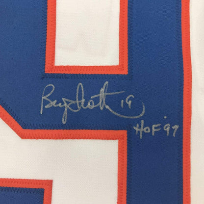 Close-up of blue jersey stripe showing handwritten gold signature "Bryan Trottier" and "HOF 97" text.