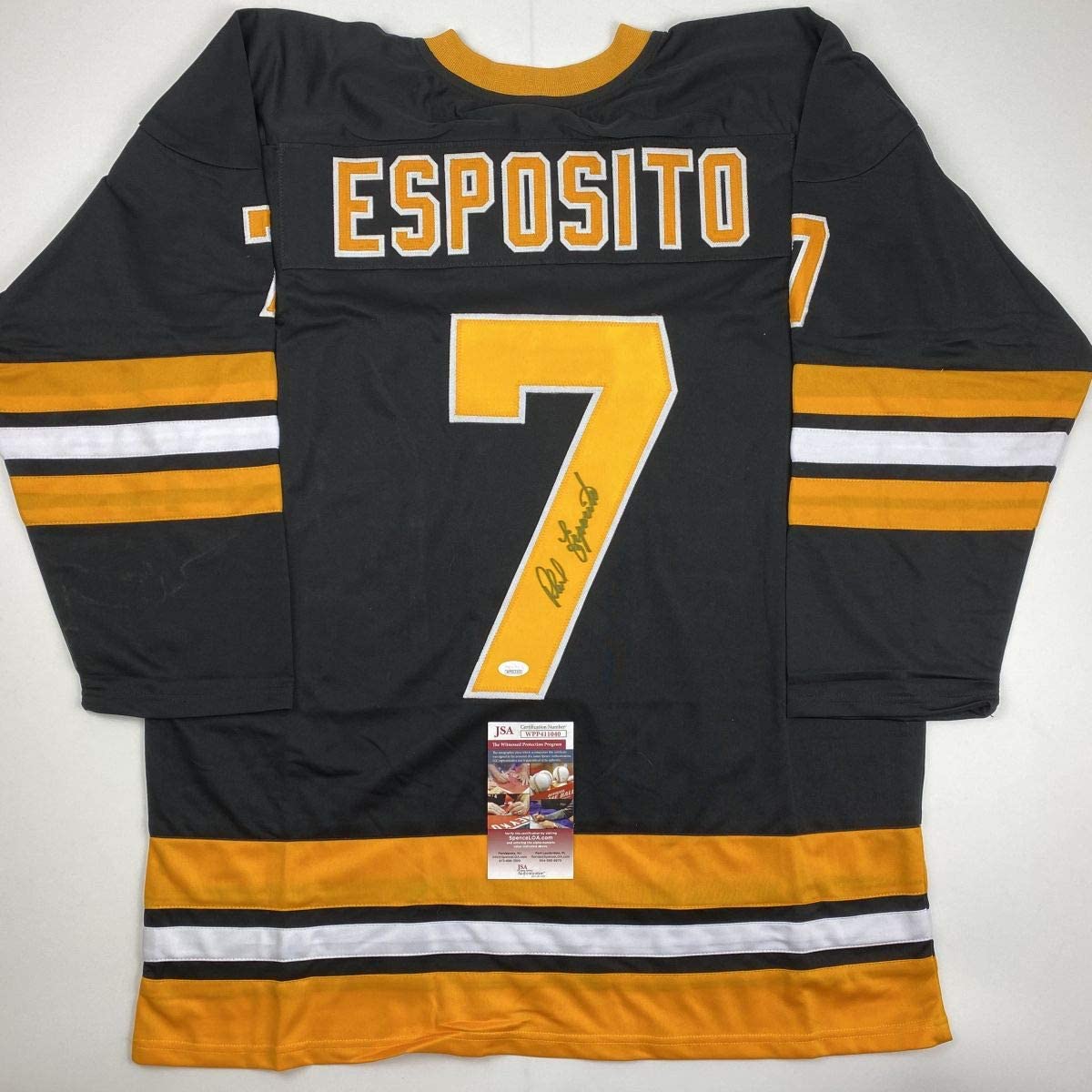 Black Boston Bruins hockey jersey number 7 with "ESPOSITO" across chest, signed in gold pen, displayed flat with JSA authentication certificate visible at bottom.