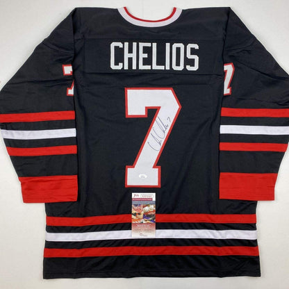 Back view of black hockey jersey with red and white horizontal stripes, "CHELIOS" nameplate, number 7, and autograph with JSA authentication label.