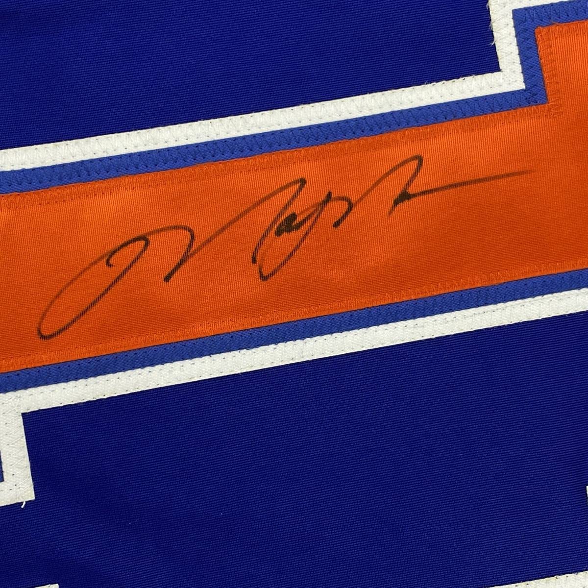Close-up of handwritten signature on orange stripe of blue and orange striped hockey jersey.