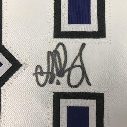Close-up of handwritten signature on white hockey jersey fabric with navy blue and black geometric design elements.