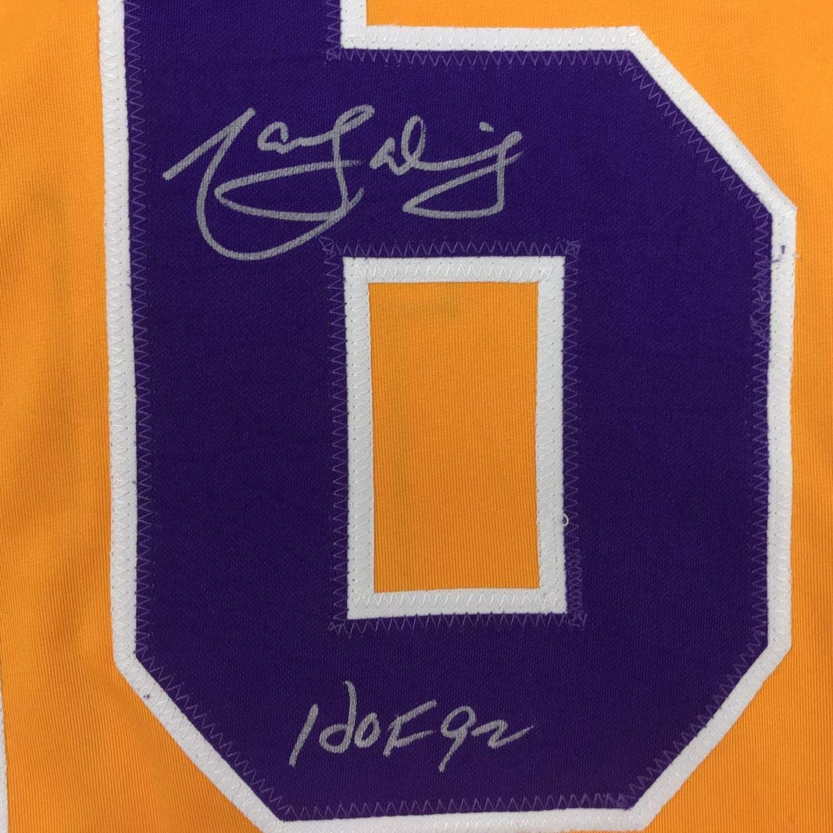 Close-up of purple jersey patch with white border showing signed autograph and "HOF92" inscription on orange background.