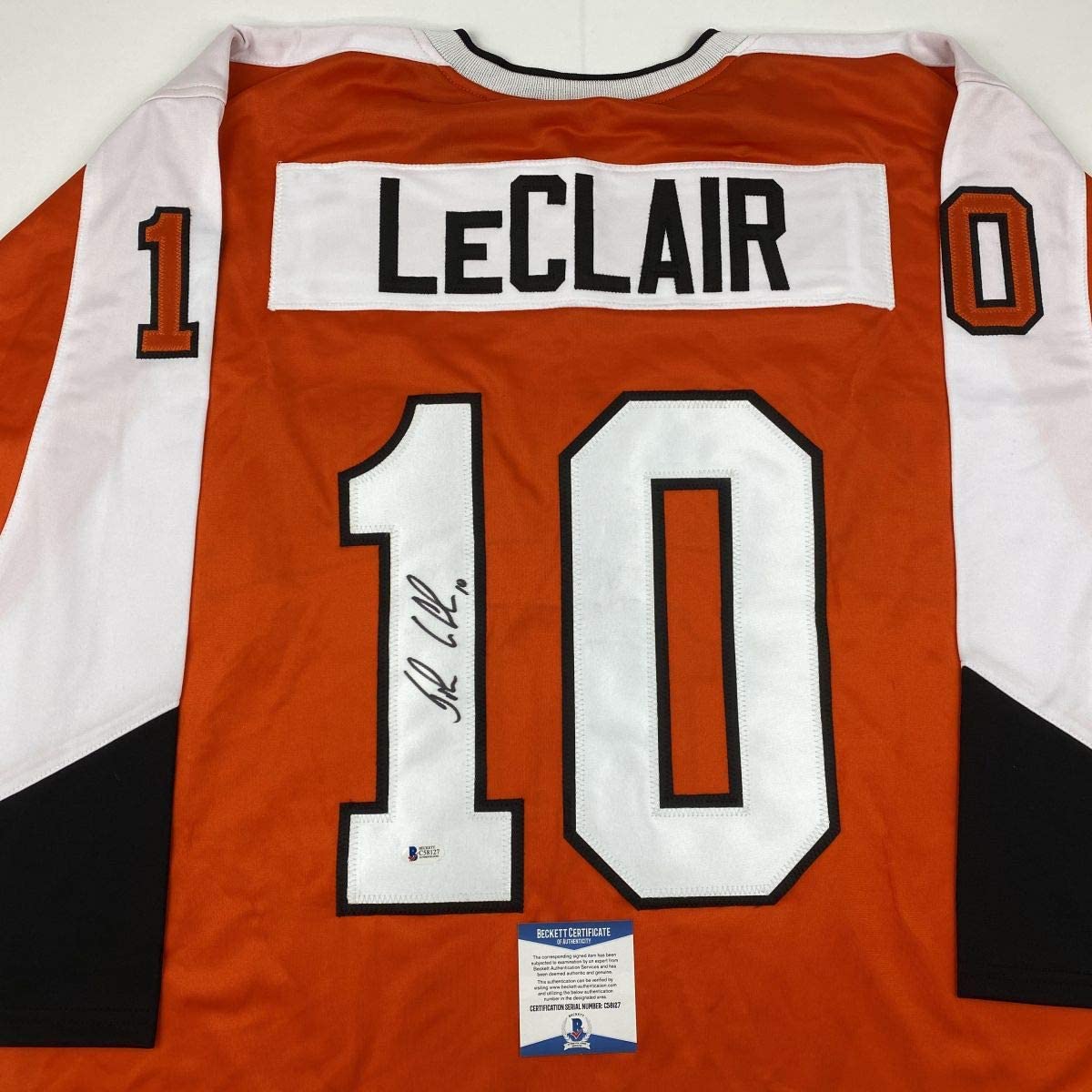 Back view of orange Philadelphia Flyers jersey number 10 with LeClair nameplate and signature, Beckett authentication sticker visible.