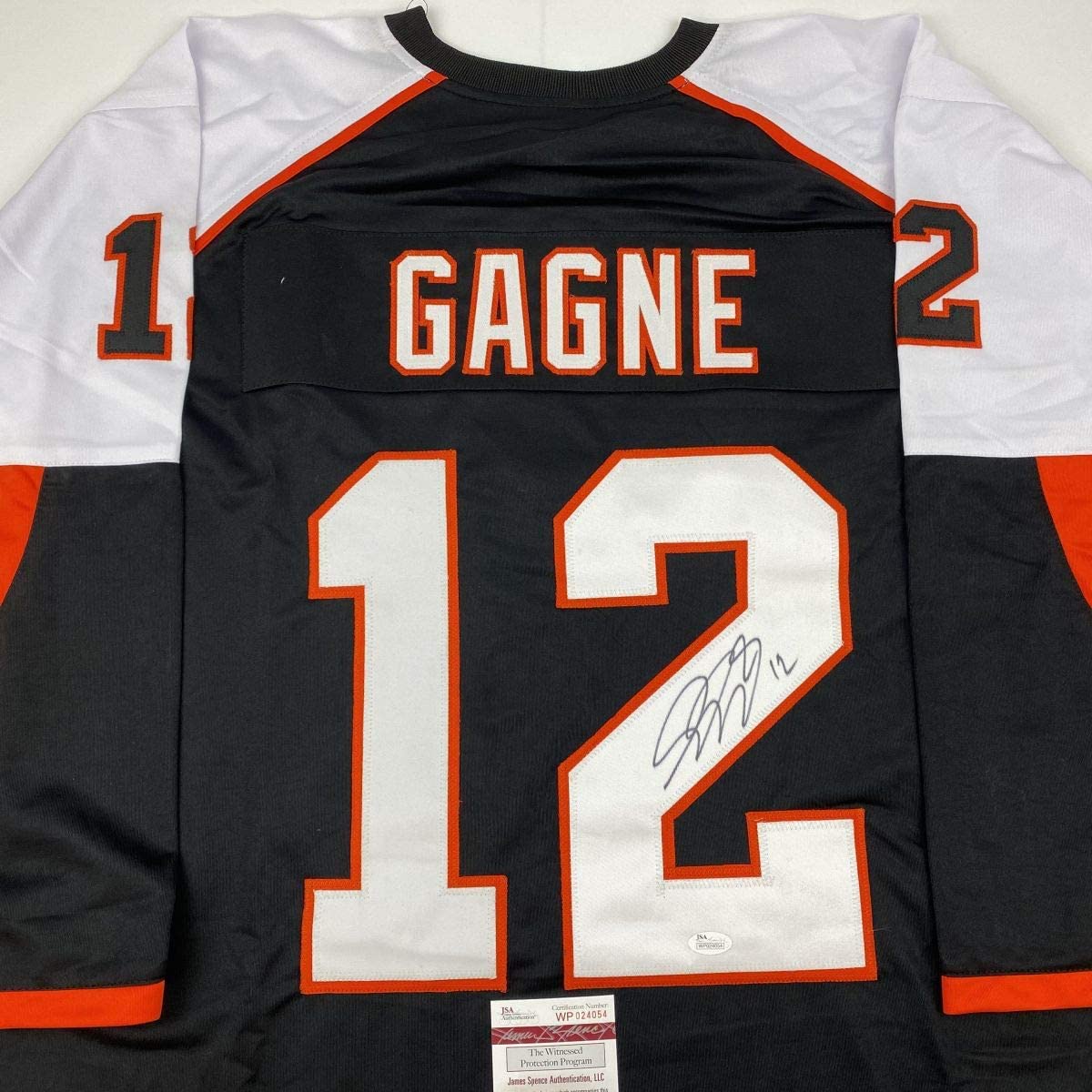 Signed black and orange Philadelphia Flyers hockey jersey number 12 with "GAGNE" nameplate, displayed flat with JSA authentication label visible at bottom.