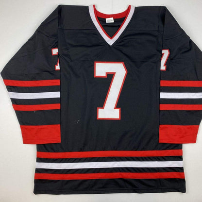 Black hockey jersey with red and white horizontal stripes, number 7 on chest and sleeves, displayed flat on white background.