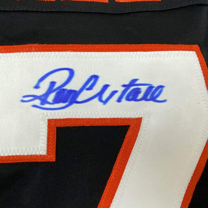 Close-up of blue "Boulton" script and orange-trimmed number 7 on white jersey panel with black and orange striping.