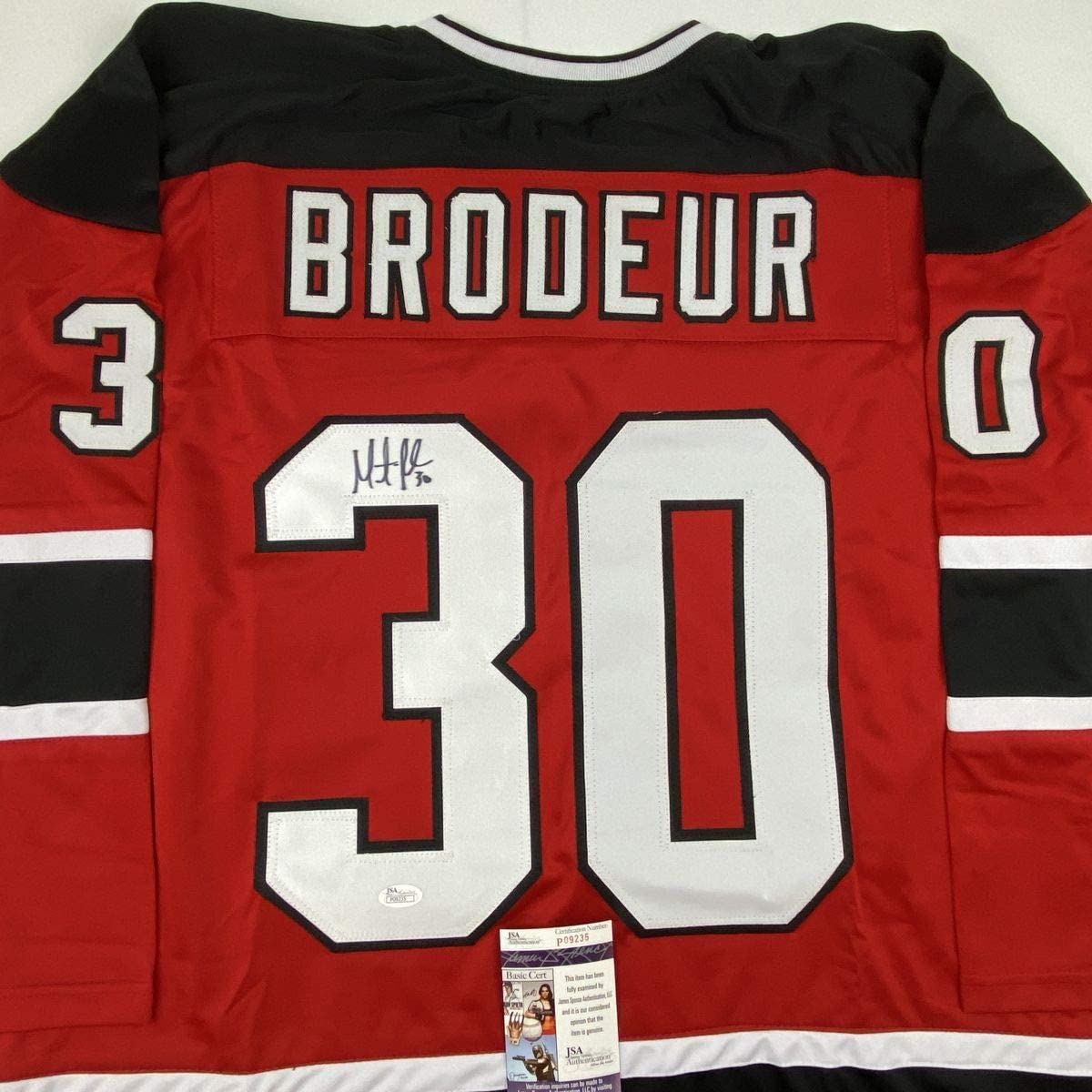 Autographed red New Jersey Devils hockey jersey number 30 with "BRODEUR" nameplate and JSA authentication certificate visible.