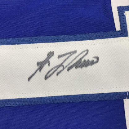 Close-up of handwritten signature in black ink on white stripe of blue and white hockey jersey.