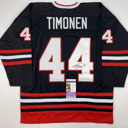Back view of black hockey jersey number 44 with "TIMONEN" nameplate, red and white stripes, autographed, with JSA authentication certificate visible at center bottom.