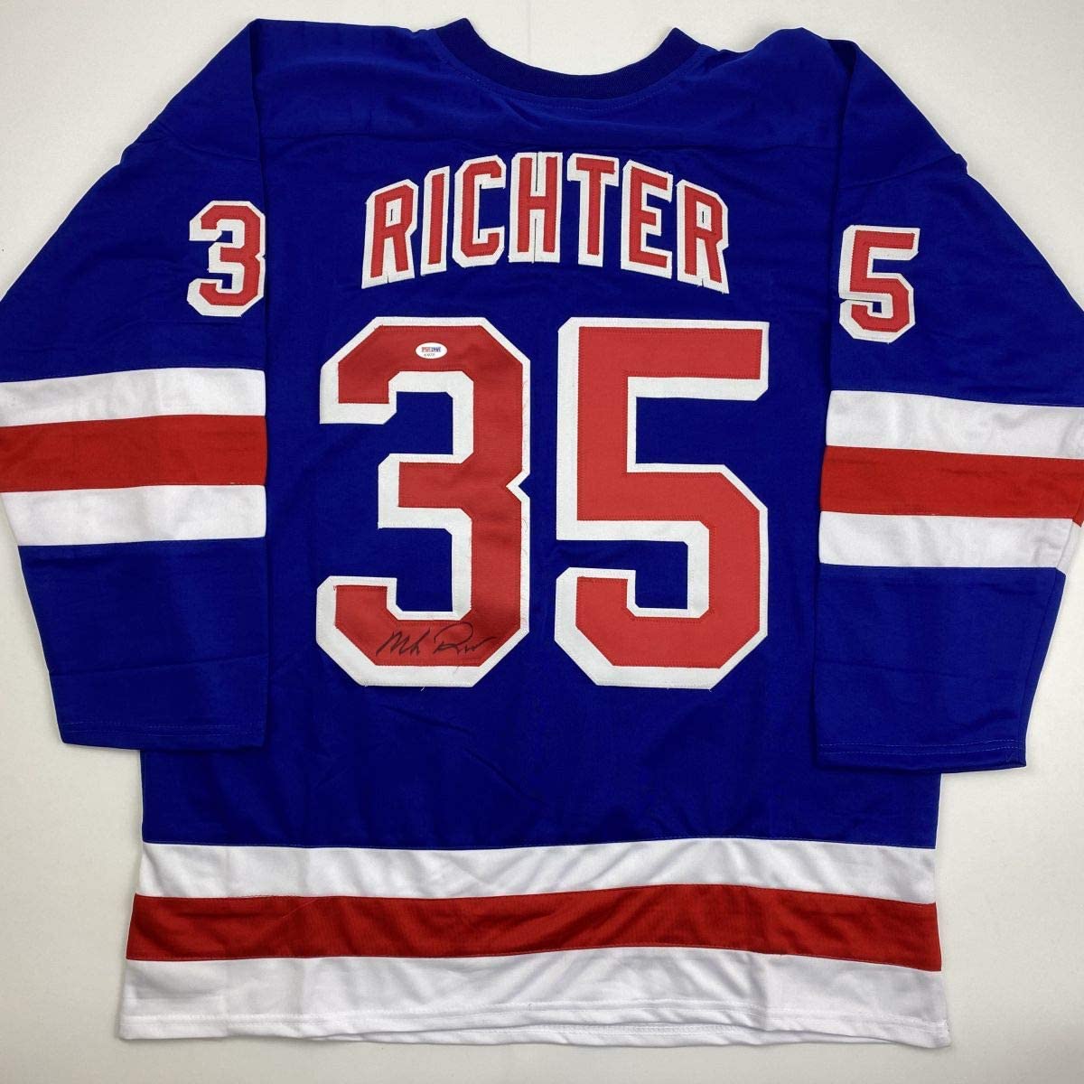 Back view of blue New York Rangers hockey jersey number 35 with "RICHTER" name and red-white stripes, displaying an autographed signature on the number.