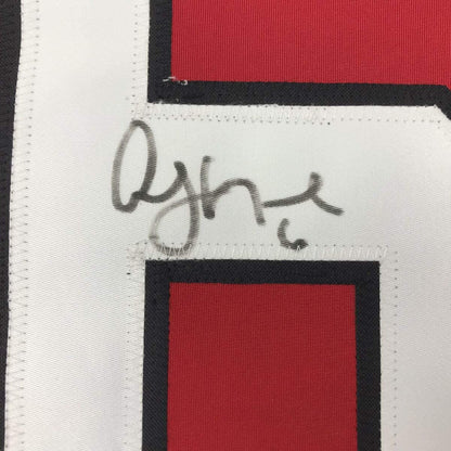 Close-up of signature on white fabric stripe of red, black, and white hockey jersey.