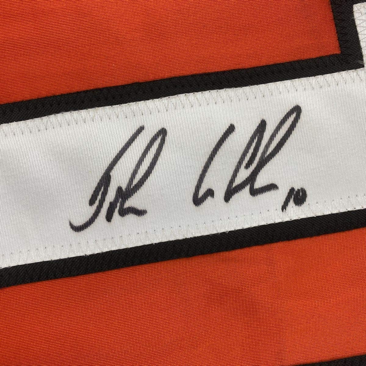 Close-up of handwritten signature on white stripe of orange and black hockey jersey.