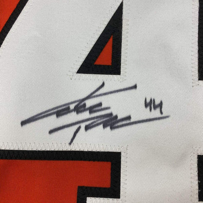 Close-up of autographed hockey jersey showing black pen signature and "44" on white fabric with red and black geometric design elements.