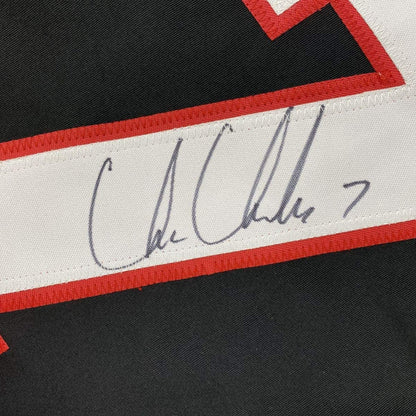 Close-up of handwritten signature on white stripe of red, white, and black hockey jersey.