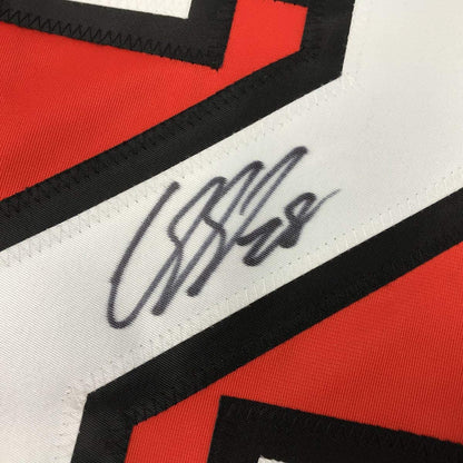 Close-up of handwritten signature on white stripe of red and black hockey jersey.