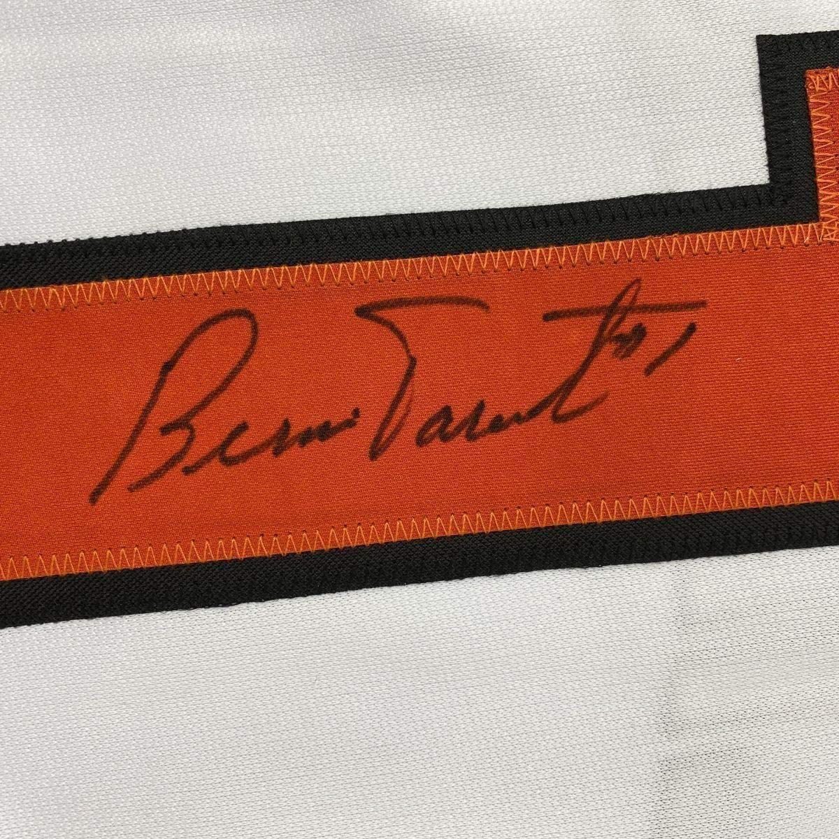 Close-up of Bernie Parent's handwritten signature in black ink on orange fabric strip with black borders.